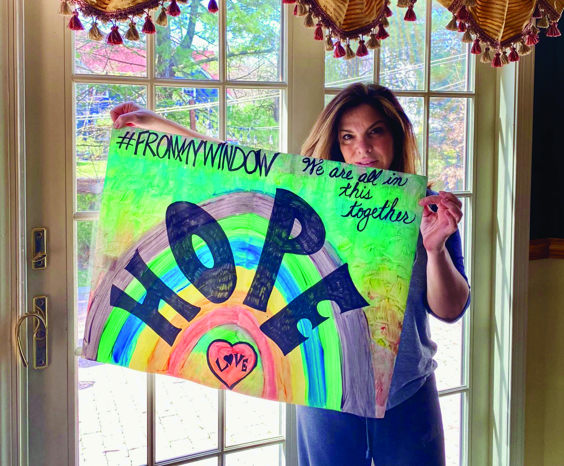 Words of Encouragement in Linden: Linden High School Principal Yelena Horre holding a poster she hung in her front window. It was part of a program in which families were encouraged to post rainbows or other uplifting messages in their front windows and doors.