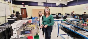 Brynn Nolan and Emma Davidson working with a Skill Boss Logistics machine, which does a buffing operation.