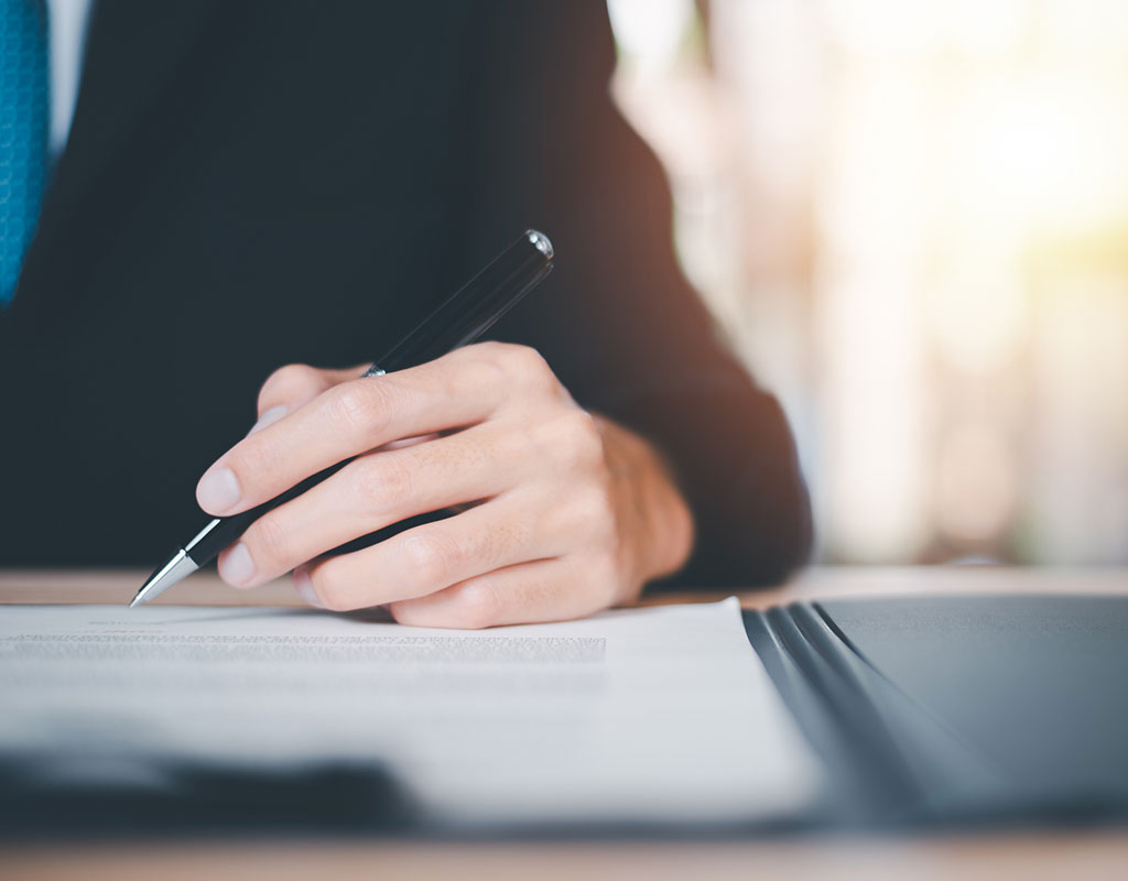 close up image of a person in a suit with ah and holding a pen to paper