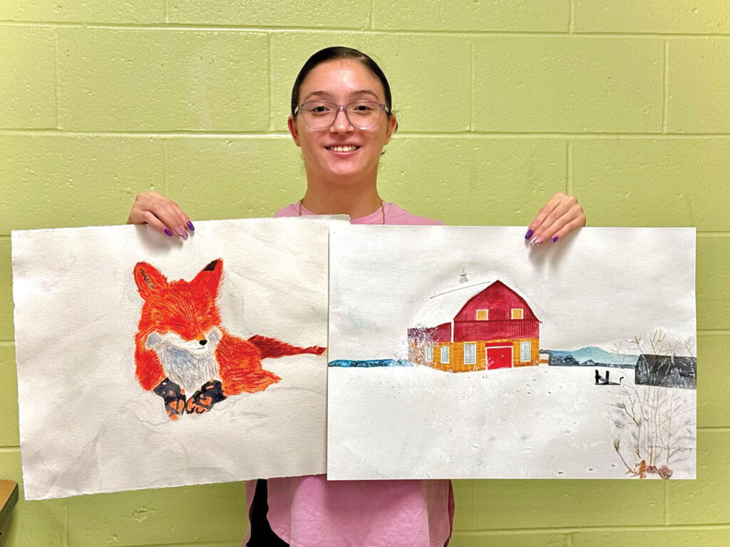 female student posing with two watercolor paintings