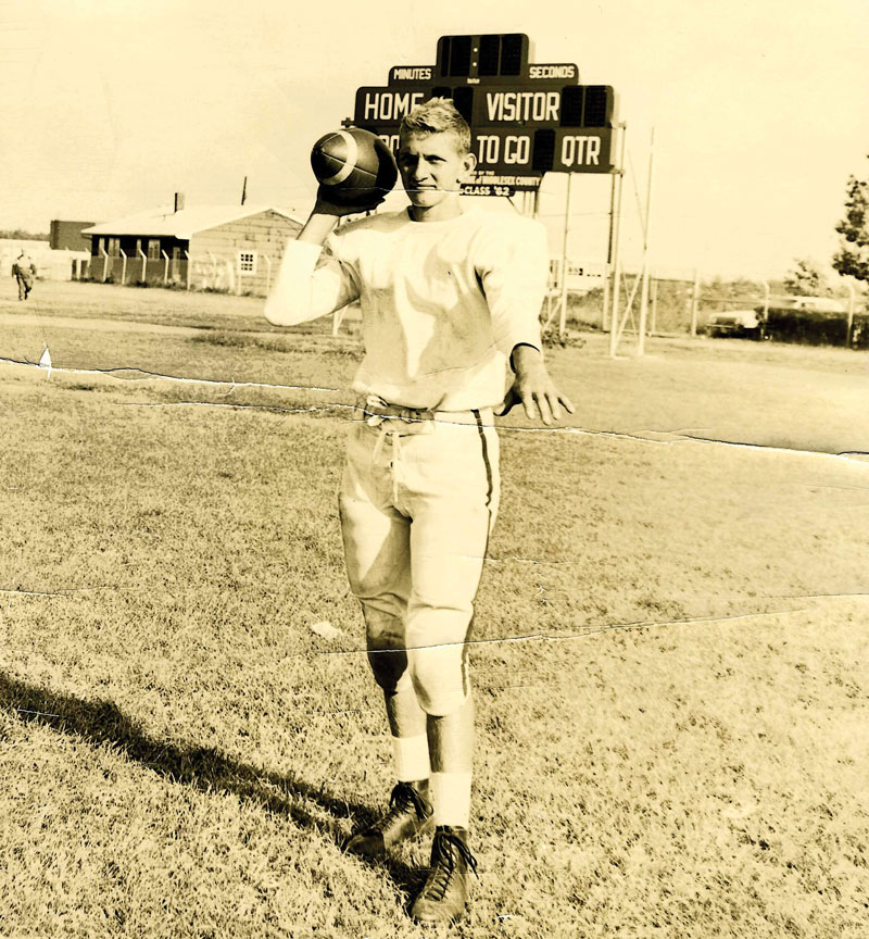 High school Joe Theismann posing with a football on the field