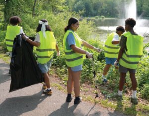 students out in a park in vests collecting trash