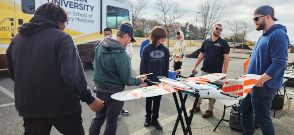 Photo of students gathered outside around a large drone