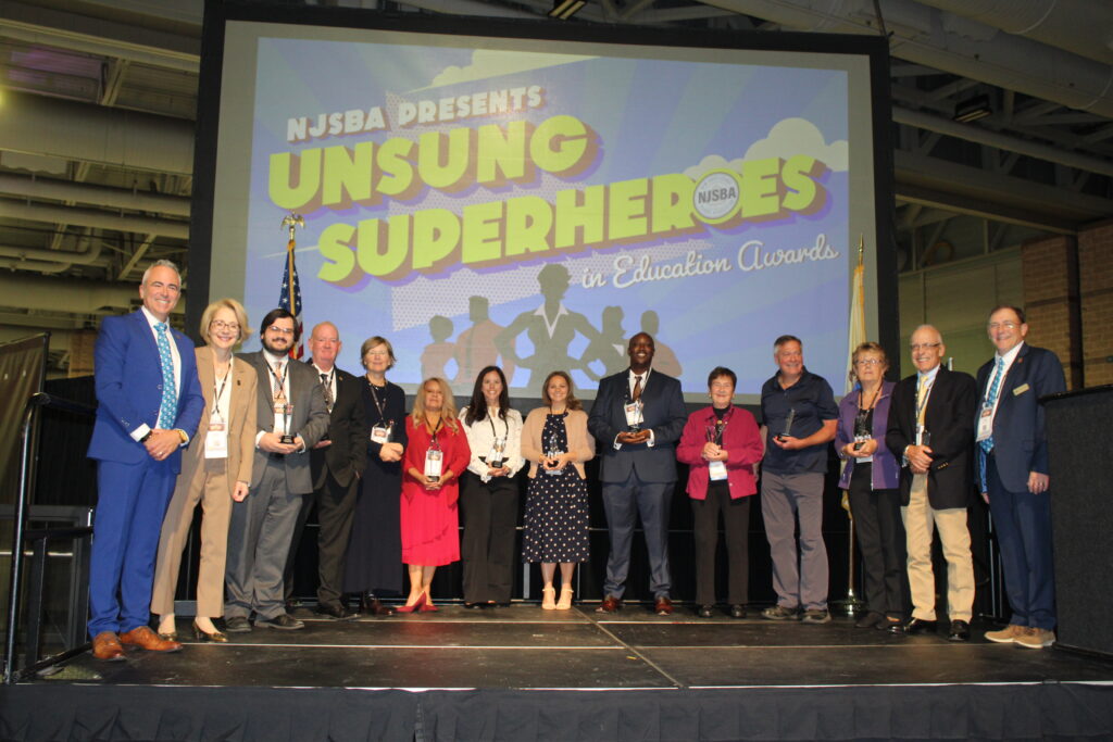 group of people posing with the unsung super heroes banner behind them