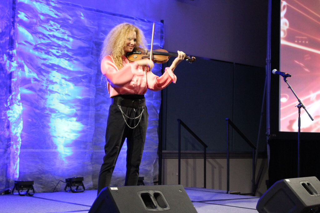 Miri Ben-Ari performing with violin at her keynote address at workshop 2025