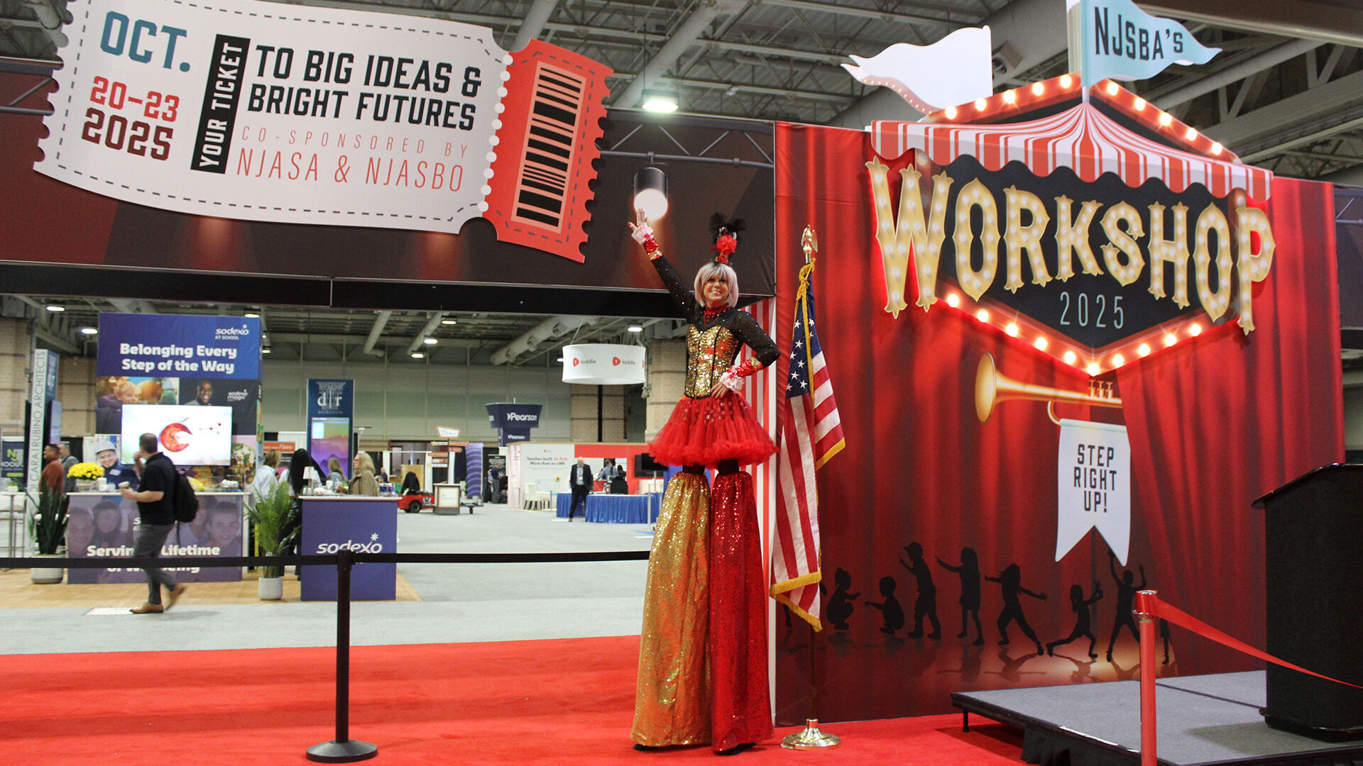 woman on stilts dressed in sequins posing in front of the workshop 2025 entrance unit