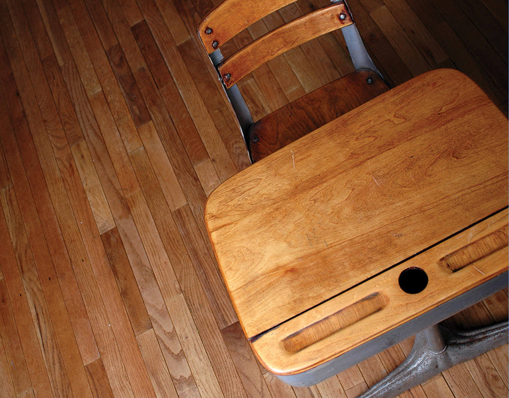 top view of an empty wooden school desk on a hardwood floor
