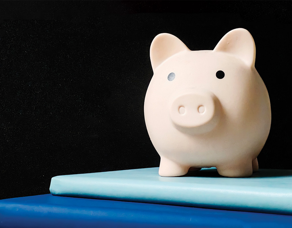 Image of a piggy bank sitting on top of two books with a black backround