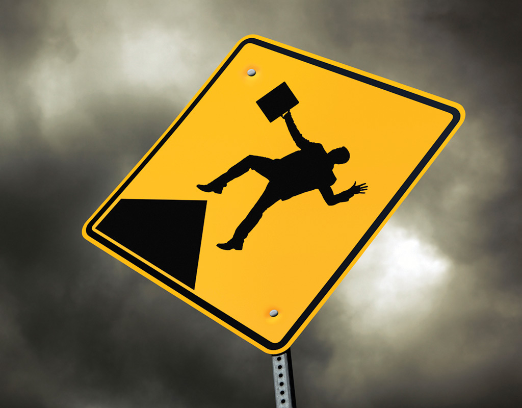 A yellow road sign with a silhouette holding a briefcase falling off a cliff
