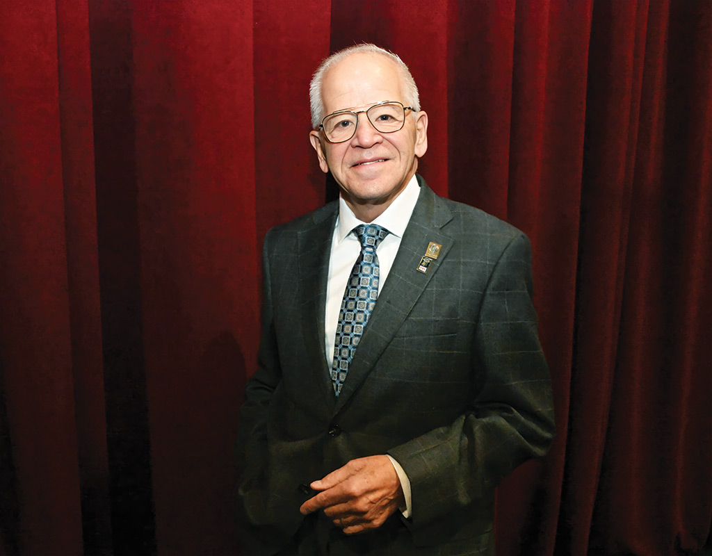 NJSBA President Michael Jacobs poses in front of a red curtain