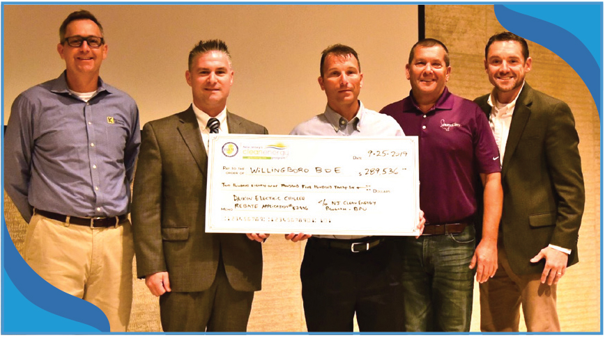 group of men posing with a giant check