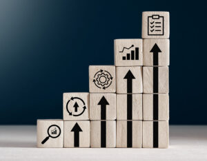 wooden blocks stacked like steps with arrows and business icons