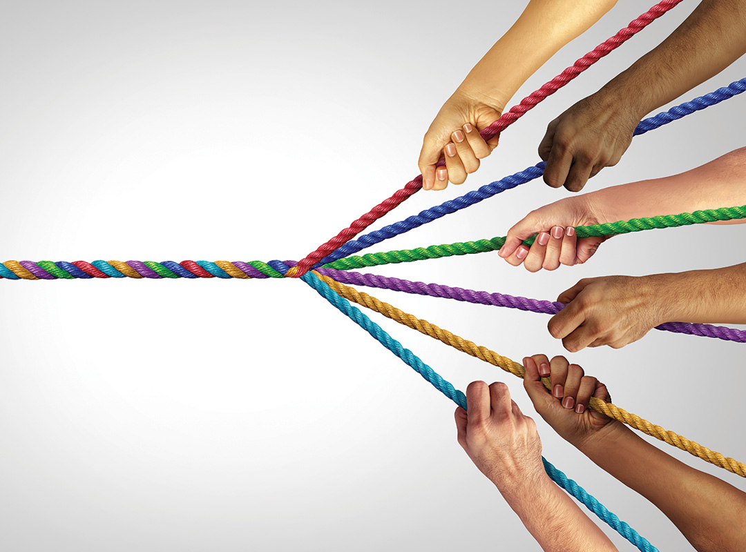 diverse hands holding a bunch of different colored ropes twisted into one single rope